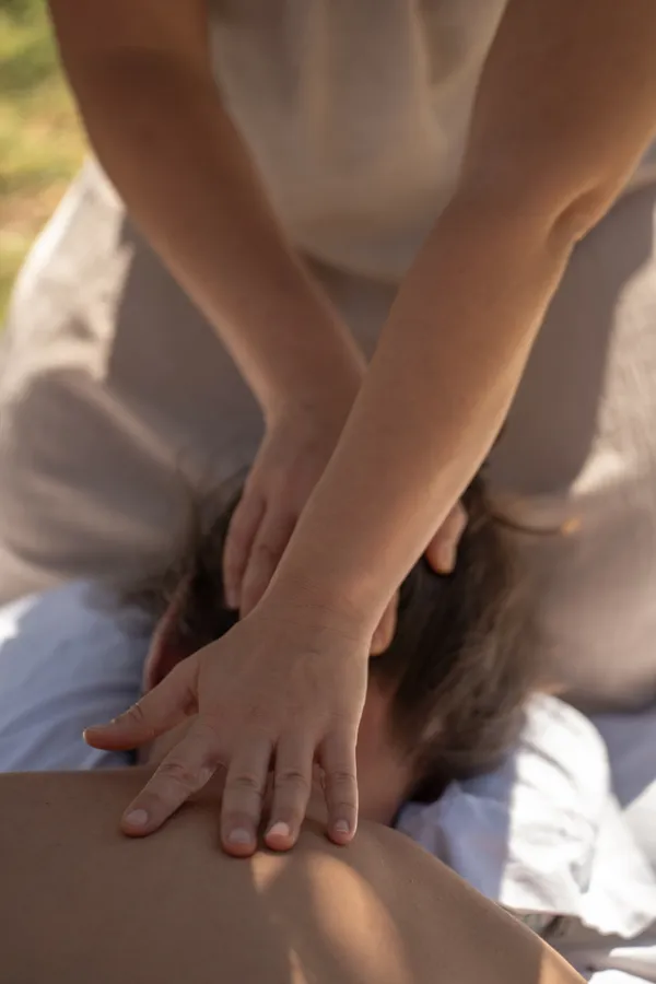Healing hands resting gently on a client's neck and back